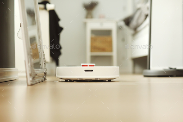 white robotic vacuum cleaner. The robot is controlled by voice commands for direct cleaning. Moder