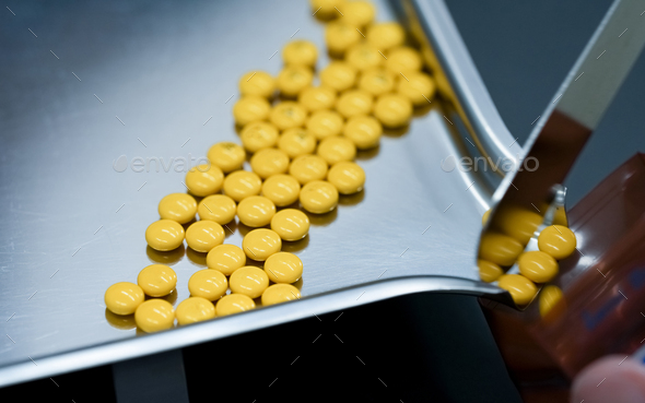 Selective focus on yellow tablets pills on stainless tray with blur hand of pharmacist or pharmacy  - Stock Photo - Images
