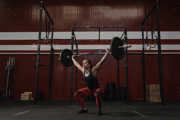 Strong woman lifting barbell overhead, doing crossfit exercises. Stock ...