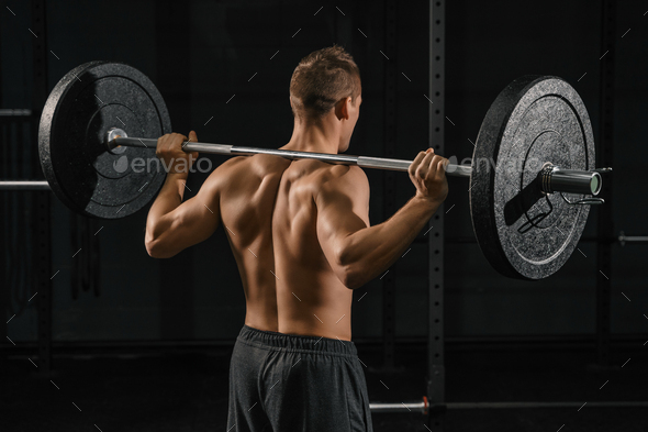 Man doing back squats exercise with a barbell.
