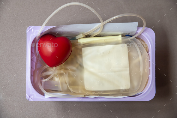 A red heart bouncy ball with blood bag in basket. Healthcare and charity. Blood donation concept