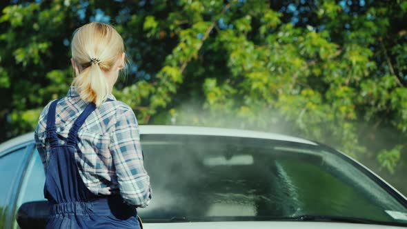 Rear View of A Woman Washing My Car in the Backyard of Her House on the Background of the Doors alt