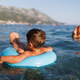 A little boy swims with an inflatable ring in the sea - PhotoDune Item for Sale