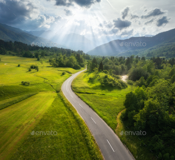 Aerial view of road in green meadows and hils at sunset in summer - Stock Photo - Images