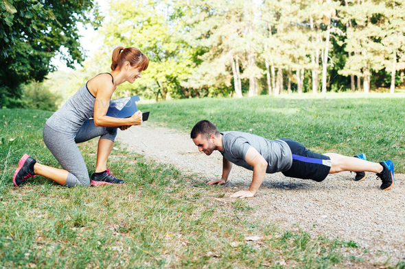 Woman trainer motivates men to do push-ups