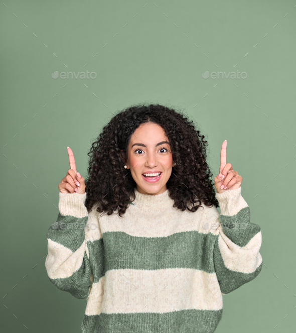 Young happy surprised latin woman pointing up isolated on green. - Stock Photo - Images