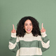 Young happy surprised latin woman pointing up isolated on green. - PhotoDune Item for Sale