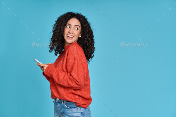Young smiling latin woman using mobile phone isolated on blue background. - Stock Photo - Images