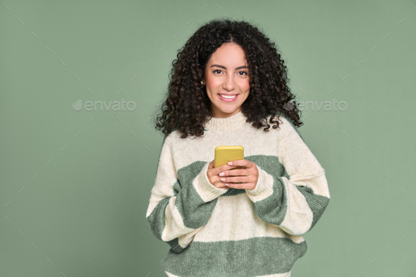Young happy latin woman using mobile phone isolated on green background. - Stock Photo - Images