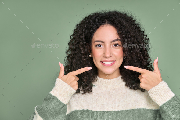Happy young woman pointing at white healthy teeth, showing perfect dental smile. - Stock Photo - Images