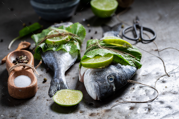 Seasoning freshl fish with salt, pepper and mint. - Stock Photo - Images