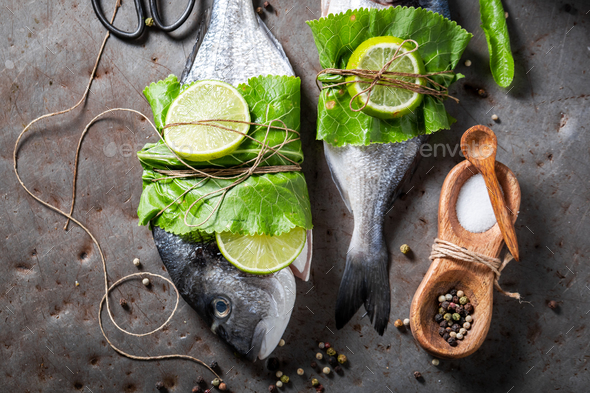 Preparing whole sea bream with horseradish leaves and lime. - Stock Photo - Images