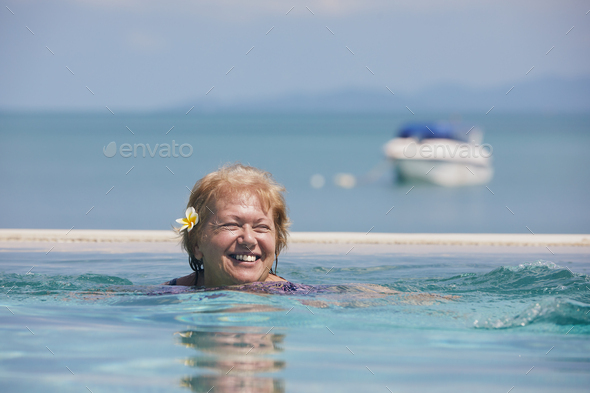 Active laughing senior woman is swimming in pool - Stock Photo - Images