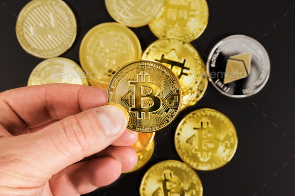 Hand of man choosing golden Bitcoin or BTC as preferred asset - Stock Photo - Images