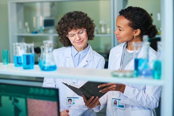 Young brunette female researcher looking at notes in notebook - Stock Photo - Images