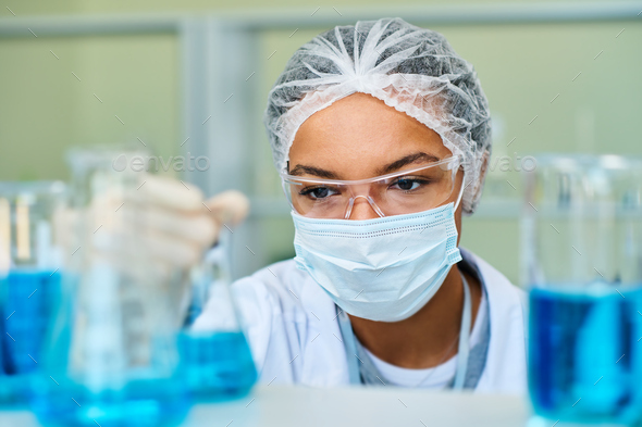 Focus on face of young African American female chemist taking test tube - Stock Photo - Images