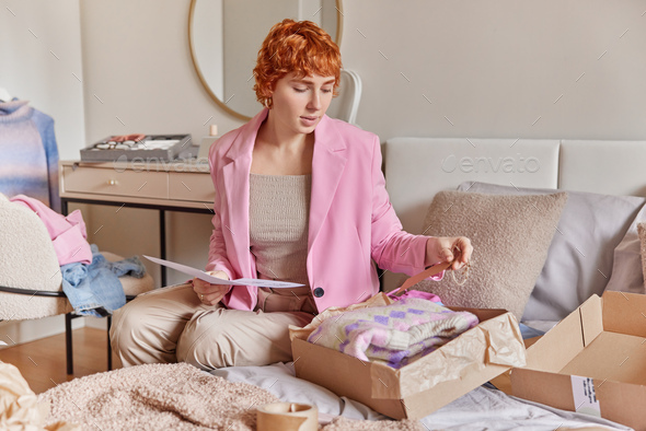Elegant female customer opens parcel cardboard holds invoice paper unpacks carton package ordered
