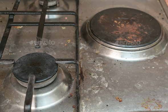 Dirty gas stove in grease stains burners in kitchen room, close up