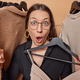 Stunned dark haired woman wears transparent eyeglasses and black dress holds clothes on hanger - PhotoDune Item for Sale