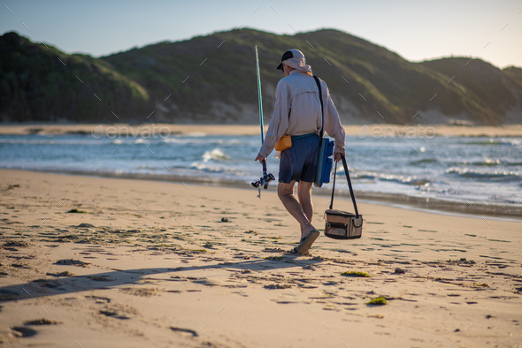 Man walking with his fishing rod along coast - Stock Photo - Images