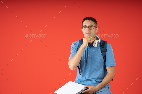 Male student with headphones and glasses, thinking about what to write in his blank notebook