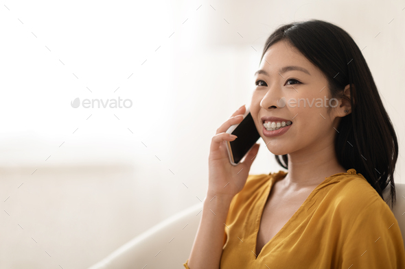 Happy beautiful asian woman having phone conversation at home, closeup - Stock Photo - Images