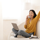 Emotional asian woman using laptop, have phone conversation, home interior - PhotoDune Item for Sale