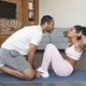 Happy young black husband helping to wife in sportswear doing abs exercises, kissing on mat - PhotoDune Item for Sale