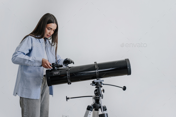 Focused brunette Italian girl in casual touches telescope using artificial bionic arm prosthesis
