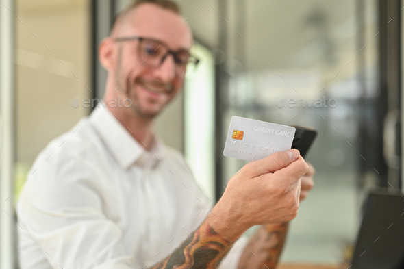 Man holding credit cad and using mobile phone smartphone for online banking transaction.