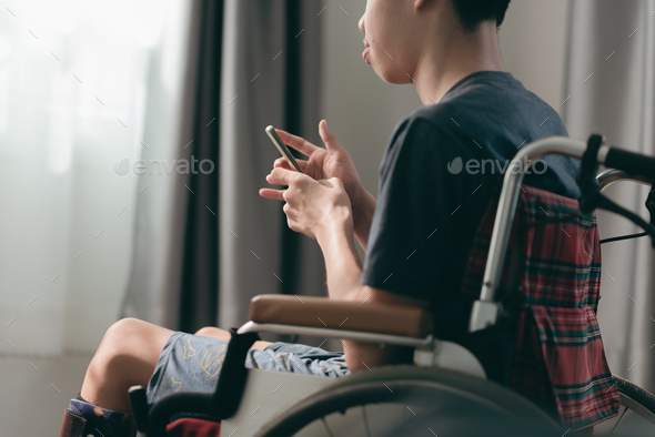 Using mobile phones to communicate and social media with disabled people on wheelchair at home - Stock Photo - Images