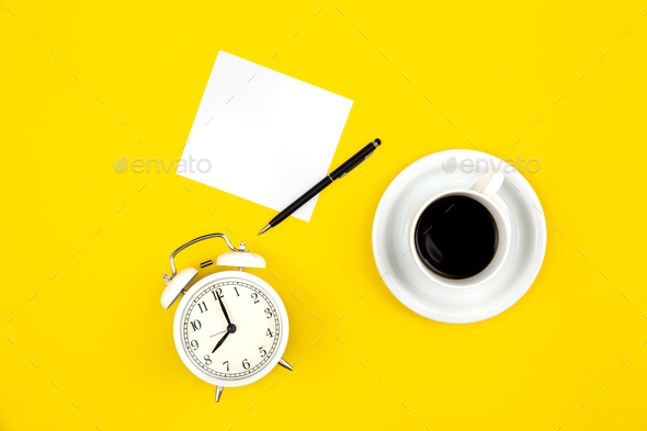 Alarm clock, cup of coffee and paper on a yellow background, flat lay. - Stock Photo - Images