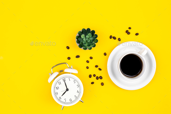 Alarm clock, cup of coffee and coffee beans on a yellow background, flat lay. - Stock Photo - Images