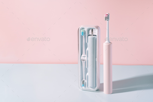 Electric toothbrush in special container against blue-pink background - Stock Photo - Images