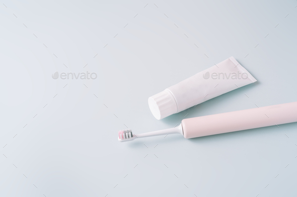 Pink electric toothbrush with toothpaste on a blue background - Stock Photo - Images