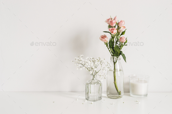 Roses, gypsophila and candle on table wall background. Romantic mockup template. Elegant minimalist