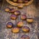 Roasted sweet chestnuts in a basket and on wood - PhotoDune Item for Sale