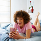 Amazed woman using smartphone on bed at home - PhotoDune Item for Sale