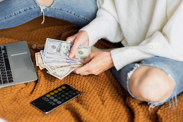 Young caucasian woman holding hands cash money dollars bills. Person counting money at home on bed - Stock Photo - Images