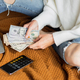 Young caucasian woman holding hands cash money dollars bills. Person counting money at home on bed - PhotoDune Item for Sale
