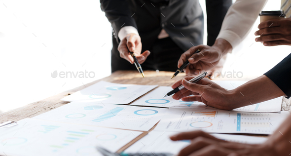 Meeting of business people pointing at graphs and charts to analyze market data, balance sheet, a - Stock Photo - Images