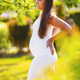 Pregnant woman in beautiful garden looking down at her belly - PhotoDune Item for Sale