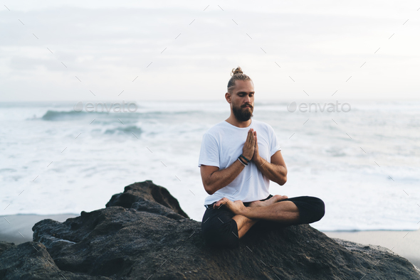 Young male in namaste asana praying mantras reaching appeasement and mindfulness