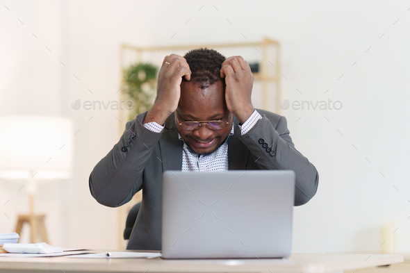 Tired American African business man in stress works with many paperwork document. migraine attack - Stock Photo - Images