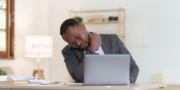 Tired American African business man in stress works with many paperwork document. migraine attack - Stock Photo - Images