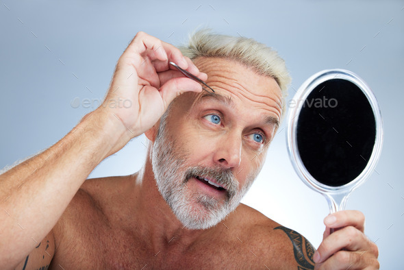 Senior man, tweezers and eyebrow in studio with mirror, grooming and self care for beauty by backgr
