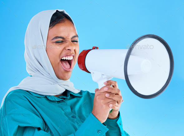 Young woman, muslim and loudspeaker in studio for protest, human rights and scream by blue backgrou