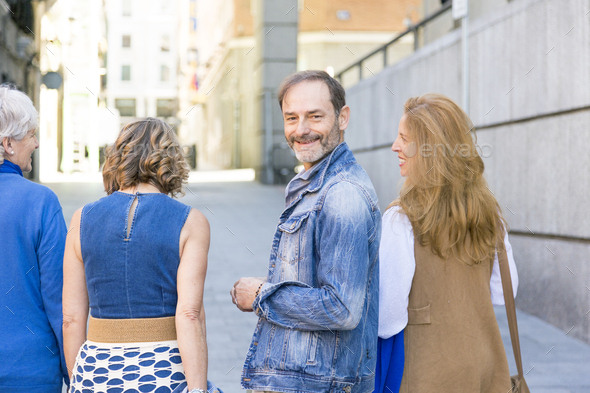 middle-aged man looking at the camera while his group of friends walk by - Stock Photo - Images