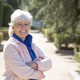 middle-aged woman with white hair smiling looking at camera with arms crossed in park - PhotoDune Item for Sale