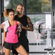 young african american sportsman embracing girlfriend with sport bottle and towel at gym - PhotoDune Item for Sale
